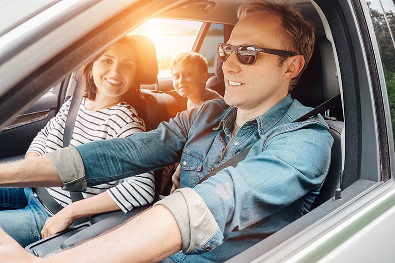 Family sitting in car while man drives happily