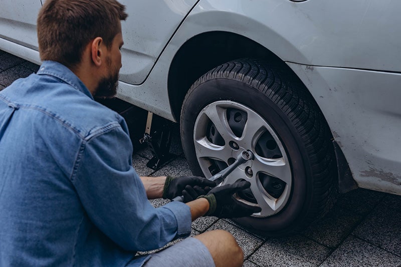Technician installing or tightening wheel on car