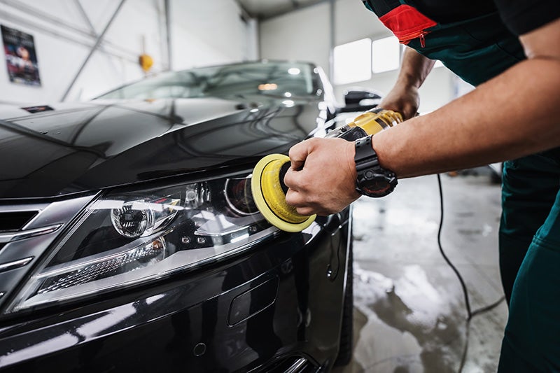 Worker polishing car headlight in repair shop